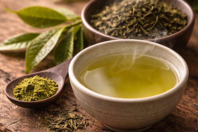 Steaming bowl of Japanese green tea with matcha powder and fresh tea leaves, representing the fresh and calming scent used in Japanese perfumes.