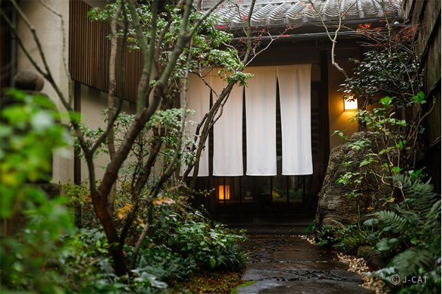Entrance to a traditional Kyoto ryotei restaurant surrounded by a serene garden setting