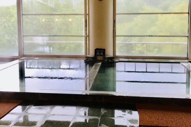Indoor bathing area at a Japanese golf club with large windows and soaking pools