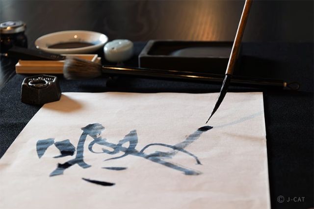 Brush writing Japanese calligraphy on paper during a traditional shodō workshop in Tokyo