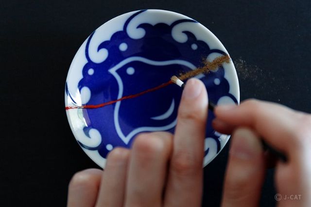 Hands repairing a Japanese ceramic plate during a traditional Kintsugi workshop in Tokyo