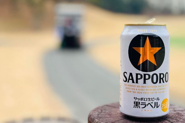 Can of Sapporo beer resting on a wooden post beside a Japanese golf course