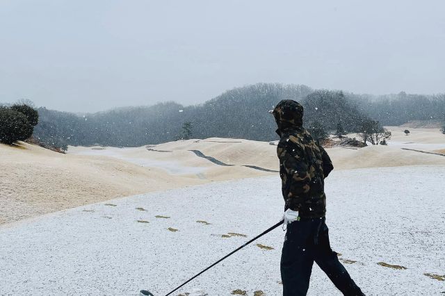 Golfer walking with club on a snow-covered golf course in Japan