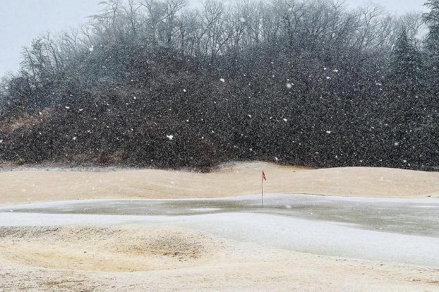 Snow-covered golf green with flag during heavy snowfall on a Japanese golf course
